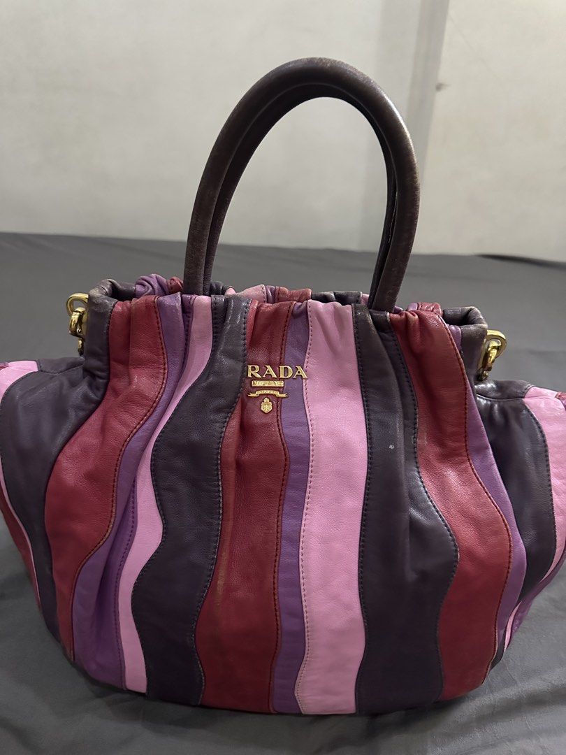 Prada Striped Leather Handbag with Shoulder Strap (Category: Luxury Bags & Wallets) located in Caloocan City. Submitted by mariecarol62420 (Listing ID 1469475649, Image 2). Description: - Brand: Prada - Design: Multicolored vertical stripes in pink, burgundy, and dark purple - Hardware: Gold-tone with centered Prada Milano logo plaque - Handles/Strap: Dual top carry handles plus an adjustable, detachable leather shoulder strap - Interior: Roomy c