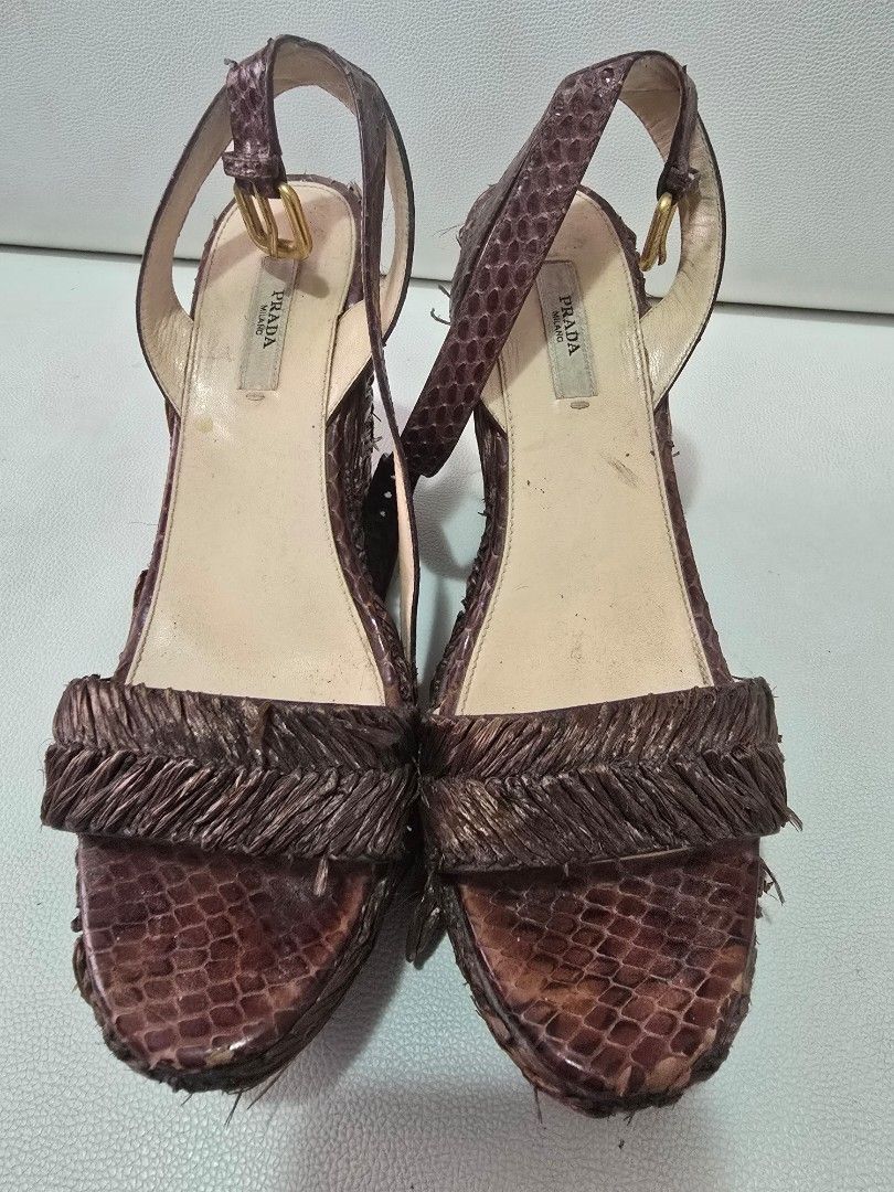 Prada Wedge Sandals Size 38 Brown Python Skin (Category: Flats & Sandals) located in Paranaque City. Submitted by shein07 (Listing ID 1469401376, Image 1). Description: - Brand: Prada - Style: Wedge sandals with ankle strap and buckle closure - Material: Brown python skin finish with straw/raffia textured details - Hardware: Gold-tone - Size: 38 (Made in Italy) - Condition: Lightly worn soles, with noticeable wear and fraying on the woven texture