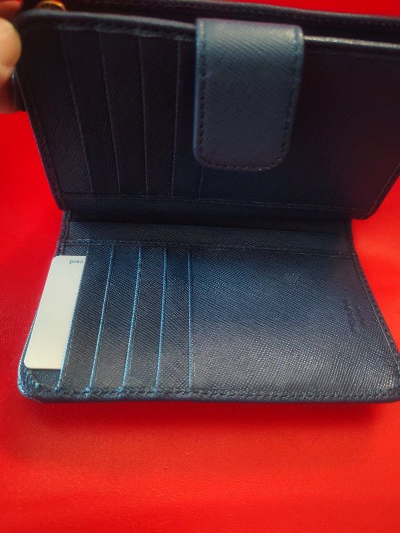 Pre loved Saffiano Leather Blue Wallet (Category: Luxury Bags & Wallets) located in Manila. Submitted by cosmicbear-ead33b (Listing ID 1469403145, Image 3). Description: - Authentic Prada wallet in sophisticated dark blue Saffiano leather - Iconic gold-toned metal logo plaque on the front - Secure snap button closure - Multiple card slots inside for easy organization - Compact size that fits effortlessly into any handbag - Immaculate stitching an