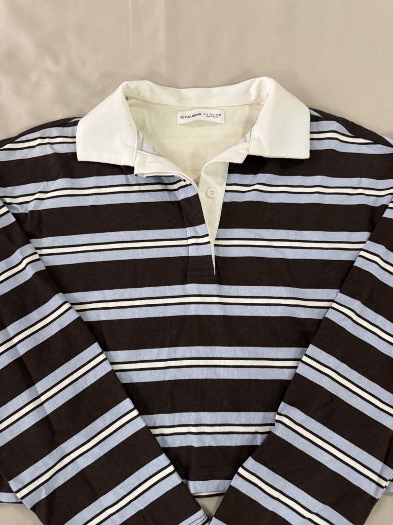 Pull&Bear Striped Long Sleeve Polo Shirt Size S (Category: Longsleeves) located in Caloocan City. Submitted by triciadrilvs (Listing ID 1469440753, Image 2). Description: - Brand: Pull&Bear - Style: Long sleeve polo shirt with brown, light blue, and white horizontal stripes - Details: Contrasting white collar and single-button placket - Size: S - Origin: Made in Morocco - Flaw: Noticeable yellowing and discoloration around the inner neckline and 