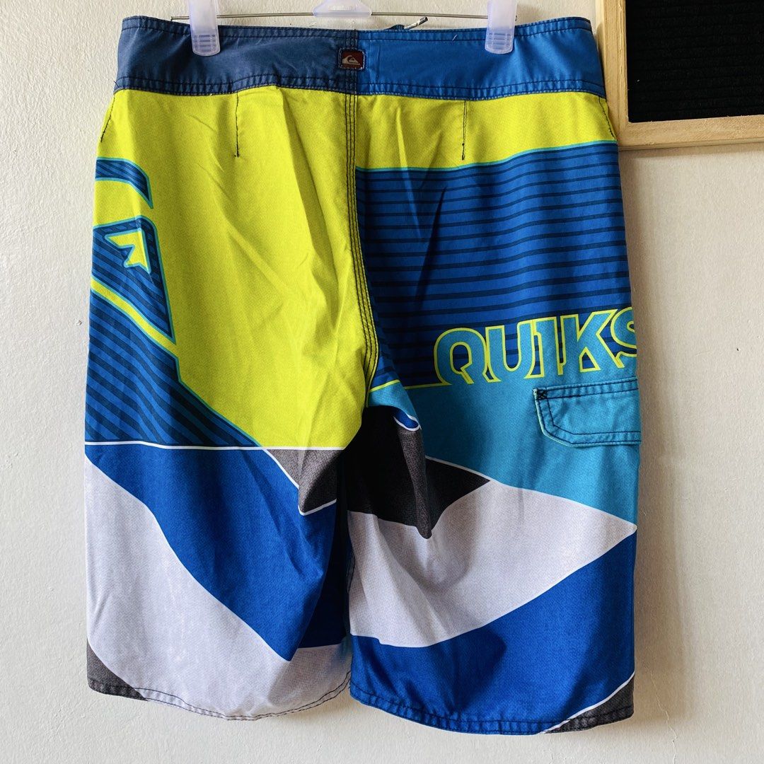 Quiksilver Men's Board Shorts (Category: Swim Trunks & Board Shorts) located in Caloocan City. Submitted by lovemyclothes21 (Listing ID 1469406618, Image 3). Description: - Brand: Quiksilver - Size: 28 - Colorway: Blue, neon yellow, white, and grey - Design: Geometric graphic print with striped details and side branding - Features: Adjustable drawstring waist, small utility pocket on the right thigh, and logo patch on the back - Condition/Use: Gr