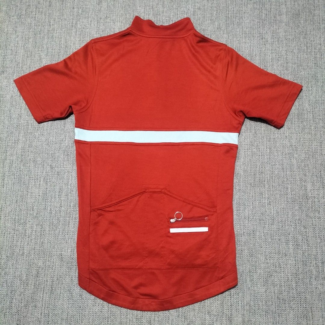 Rapha Short Sleeve Cycling Jersey Red White (Category: Activewear) located in Taytay. Submitted by calmtree-6248 (Listing ID 1469536803, Image 3). Description: - Brand: Rapha - Color: Bright red with light blue chest stripe - Design: Short sleeve, half zip neck closure, and high collar - Fit/Features: Dropped hem with black and white grip band at the back - Material: Lightweight, breathable fabric ideal for road cycling - Condition: Clean bright 