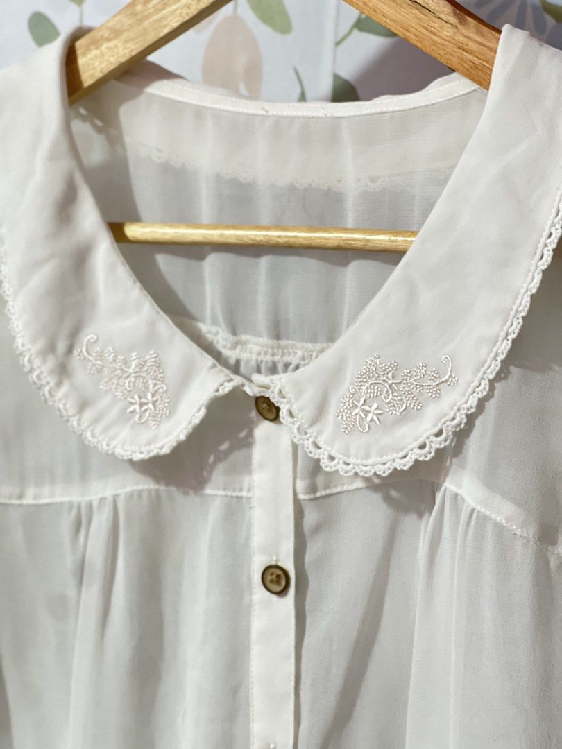 Ray Cassin White Embroidered Peter Pan Collar Blouse (Category: Blouses) located in Pasig City. Submitted by morilove (Listing ID 1469420480, Image 2). Description: - Brand: Ray Cassin - Color: White - Size/Material: 100% lightweight polyester (semi-sheer), made in China - Design: Short sleeves, Peter Pan collar with delicate floral embroidery and scalloped lace trim - Details: Front button closure with brown buttons, gathered yoke detail on the 