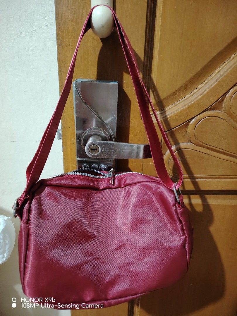 Red Shoulder Bag with Zipper Pockets (Category: Shoulder Bags) located in Manila. Submitted by justybelieve2026 (Listing ID 1469451778, Image 2). Description: - Vibrant red nylon-feel material with a durable build - Secure main zipper closure to keep your belongings safe - Convenient front zip pocket featuring a stylish metal pull tab - Elegant silver-tone brand logo plate on the lower right corner - Adjustable strap on both sides for a customize