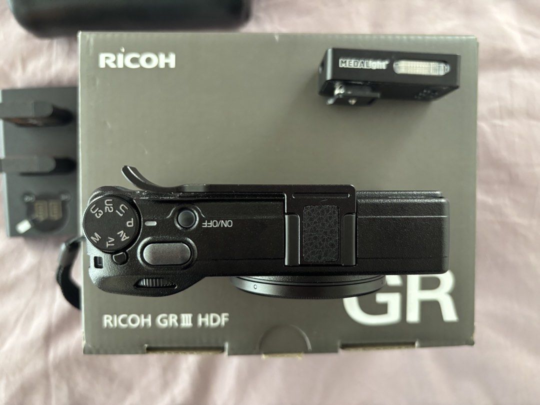 Ricoh GR III HDF Digital Camera with Accessories (Category: Cameras) located in Quezon City. Submitted by chinchiminni (Listing ID 1469426803, Image 2). Description: - Camera: Ricoh GR III HDF compact camera (includes original box) - Condition: Clean body with minimal signs of handling - Accessories included: Dual battery charger, black leather case, thumb grip attachment, and Medalight mini flash unit - Extra: Wrist strap securely attached - Hig