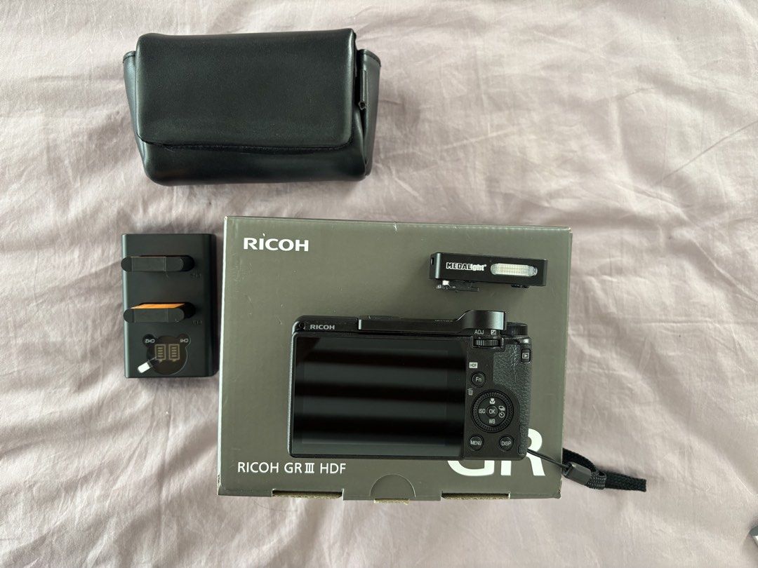 Ricoh GR III HDF Digital Camera with Accessories (Category: Cameras) located in Quezon City. Submitted by chinchiminni (Listing ID 1469426803, Image 3). Description: - Camera: Ricoh GR III HDF compact camera (includes original box) - Condition: Clean body with minimal signs of handling - Accessories included: Dual battery charger, black leather case, thumb grip attachment, and Medalight mini flash unit - Extra: Wrist strap securely attached - Hig