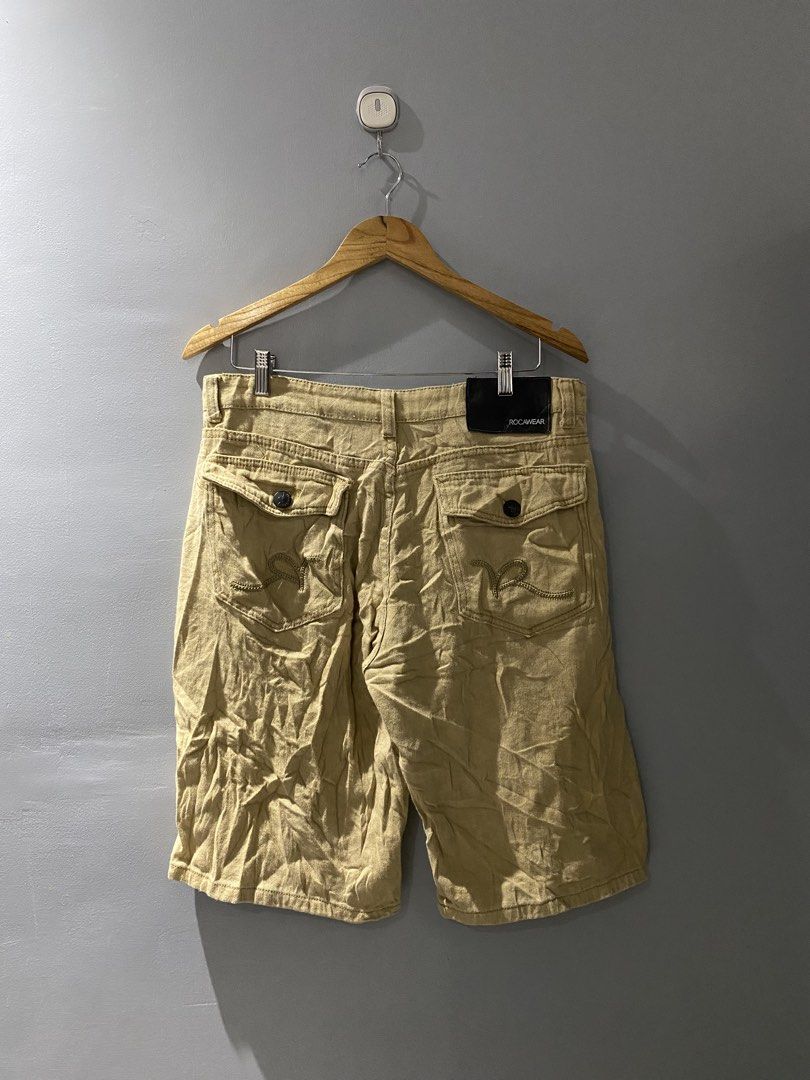 Rocawear Khaki Cargo Shorts (Category: Shorts) located in Bangued. Submitted by koroysthrifts (Listing ID 1469519088, Image 2). Description: 34x23x11.5 Rocawear khaki cargo shorts in a tan shade. Heavy twill fabric construction with multiple utility pockets on the back and sides. Embroidered logo detailing on the back pocket flap and front coin pocket. Button fly closure and branded waistband tag. Solid streetwear staple..