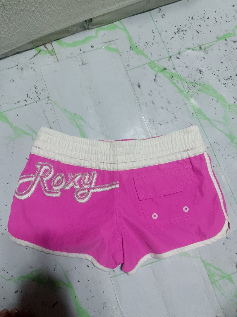 Roxy pink boardshorts size 8 with sparkly logo (Category: Shorts) located in Antipolo. Submitted by y2k_outfitters. (Listing ID 1469516612, Image 1). Description: - Brand: Roxy - Style: Y2K surf style bright pink boardshorts - Size: Tagged Size 8 - Features: White elastic waistband with drawstring, sparkly silver Roxy script logo on left leg, and small back pocket with grommets - Origin: Made in China.