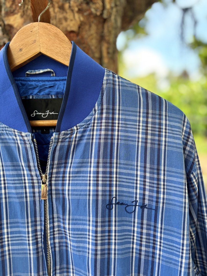 Sean John Blue Plaid Bomber Jacket Size L (Category: Coats, Jackets and Outerwear) located in San Jacinto. Submitted by ticao_thrift (Listing ID 1469571807, Image 3). Description: - Brand: Sean John - Size: L - Style: Blue plaid bomber jacket with zip-up front - Details: Signature embroidered logo on chest, deep blue smooth inner lining, and front hand pockets - Fit: Comfortable fit, ribbed collar, cuffs, and hem - Condition: Great vintage street