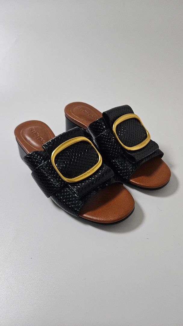 See By Chloe Black Sandals (Category: Flats & Sandals) located in Alfonso. Submitted by jbcamet (Listing ID 1469511108, Image 1). Description: - Brand: See By Chloe - Style: Sandals with low block heels - Size: EU 37 - Color/Pattern: Black with snakeskin texture - Details: Chunky gold buckle hardware, brown leather footbeds - Condition: Good pre-loved condition with light scuffing on the soles from past wear.