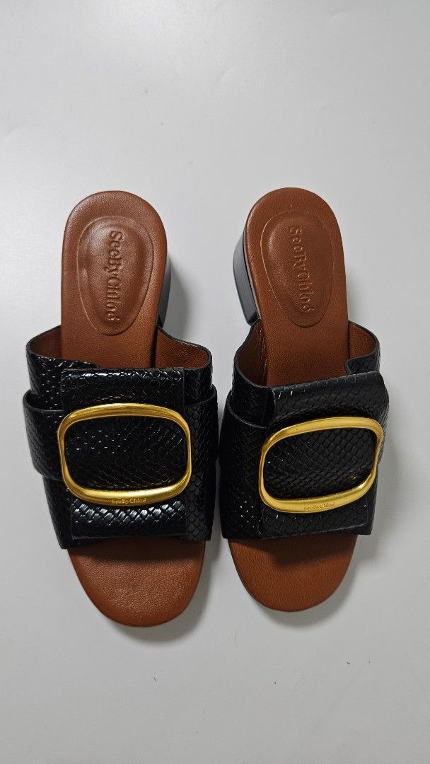See By Chloe Black Sandals (Category: Flats & Sandals) located in Alfonso. Submitted by jbcamet (Listing ID 1469511108, Image 3). Description: - Brand: See By Chloe - Style: Sandals with low block heels - Size: EU 37 - Color/Pattern: Black with snakeskin texture - Details: Chunky gold buckle hardware, brown leather footbeds - Condition: Good pre-loved condition with light scuffing on the soles from past wear.
