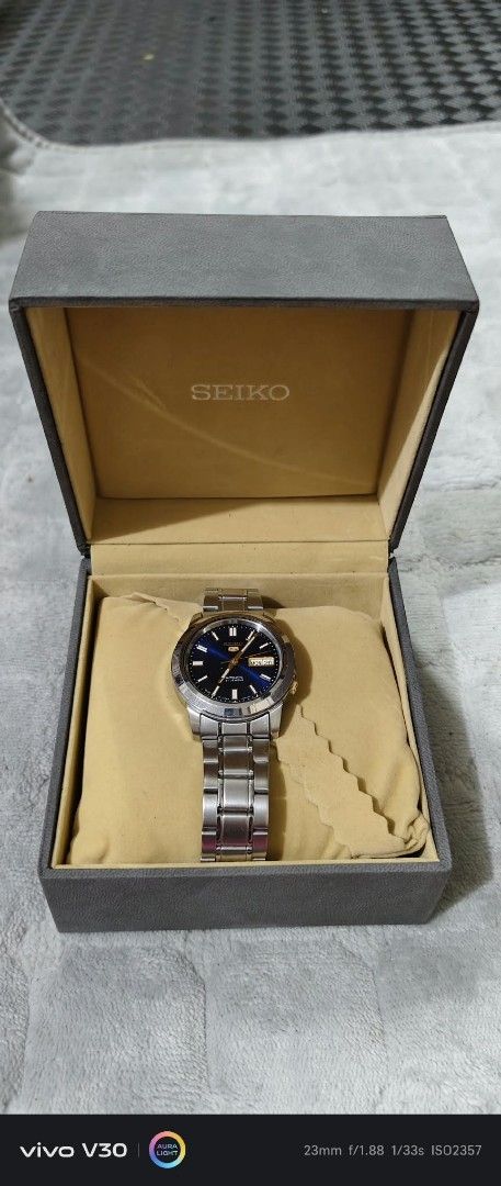 Seiko 5 Automatic 21 Jewels Blue Dial Watch (Category: Men's Watches) located in Taguig. Submitted by thrifthub.ph (Listing ID 1469443944, Image 1). Description: - Brand: Seiko 5 Automatic - Dial: Striking blue sunburst face with gold-tone hands and hour markers - Features: Day and date window at the 3 o'clock position, crown at 4 o'clock - Material: Durable stainless steel case and bracelet - Inclusions: Comes with the original watch box as show