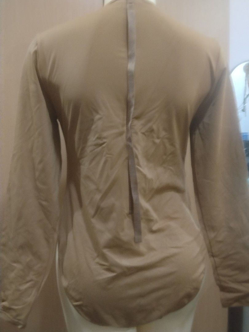 SKIMS Mock Neck Long Sleeve Bodysuit Tan (Category: Longsleeves) located in Manila. Submitted by ajrswimwear (Listing ID 1469556439, Image 3). Description: - Brand: SKIMS - Style: Mock neck, long sleeve bodysuit with high-cut leg opening - Color: Neutral tan - Fabric: Smooth and stretchy - Closure: Bottom snaps - Condition: Brand new with original tags attached, never worn.