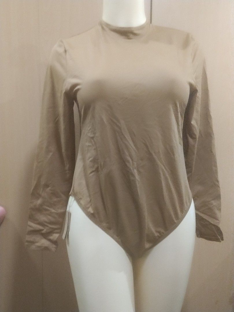SKIMS Mock Neck Long Sleeve Bodysuit Tan (Category: Longsleeves) located in Manila. Submitted by ajrswimwear (Listing ID 1469556439, Image 1). Description: - Brand: SKIMS - Style: Mock neck, long sleeve bodysuit with high-cut leg opening - Color: Neutral tan - Fabric: Smooth and stretchy - Closure: Bottom snaps - Condition: Brand new with original tags attached, never worn.