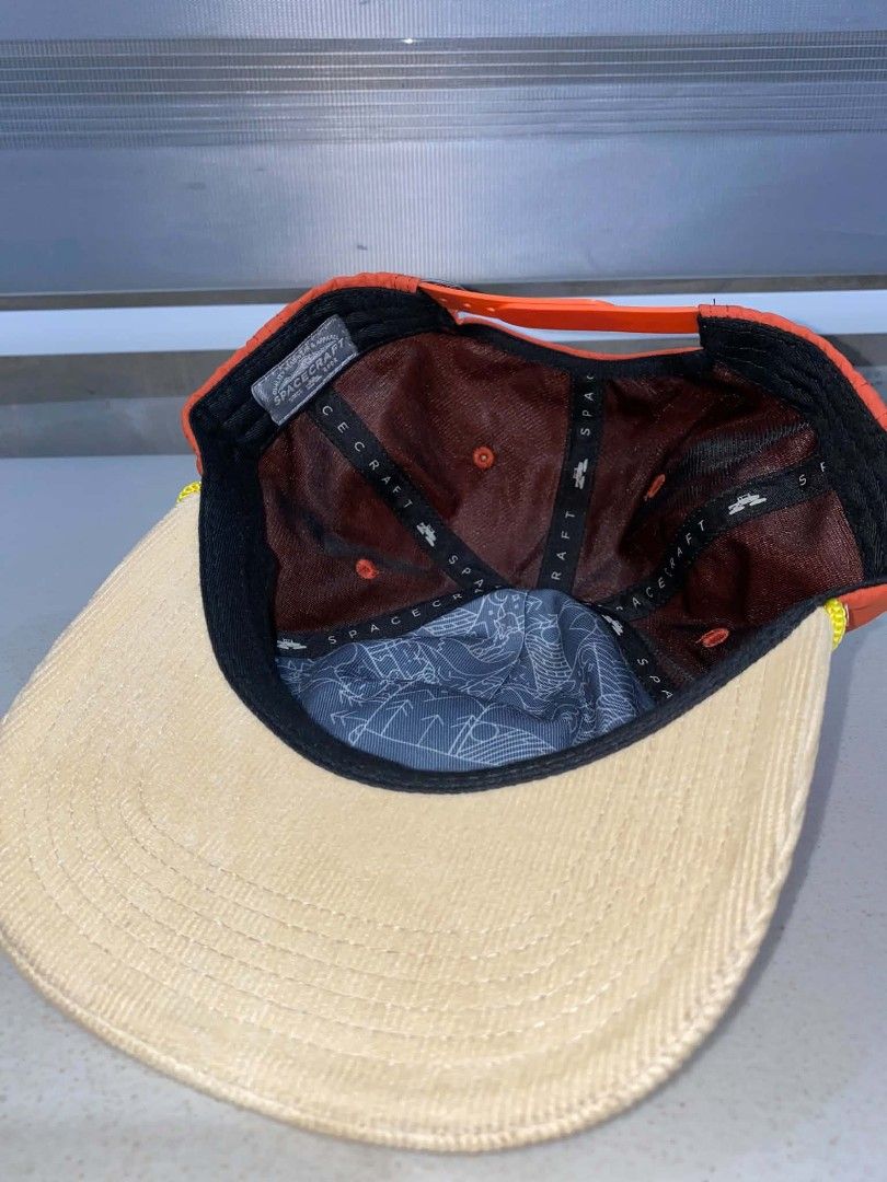Spacecraft Orange and Cream Snapback Hat (Category: Caps & Hats) located in Baler. Submitted by mariokush193815 (Listing ID 1469452747, Image 3). Description: - Brand: Spacecraft - Style: Snapback cap in bright orange and cream corduroy - Details: Round embroidered mountain, star, and moon patch on the front - Accents: Yellow cord trim along the brim and patterned blue lining underneath - Fit: Adjustable orange plastic strap at the back - Conditi
