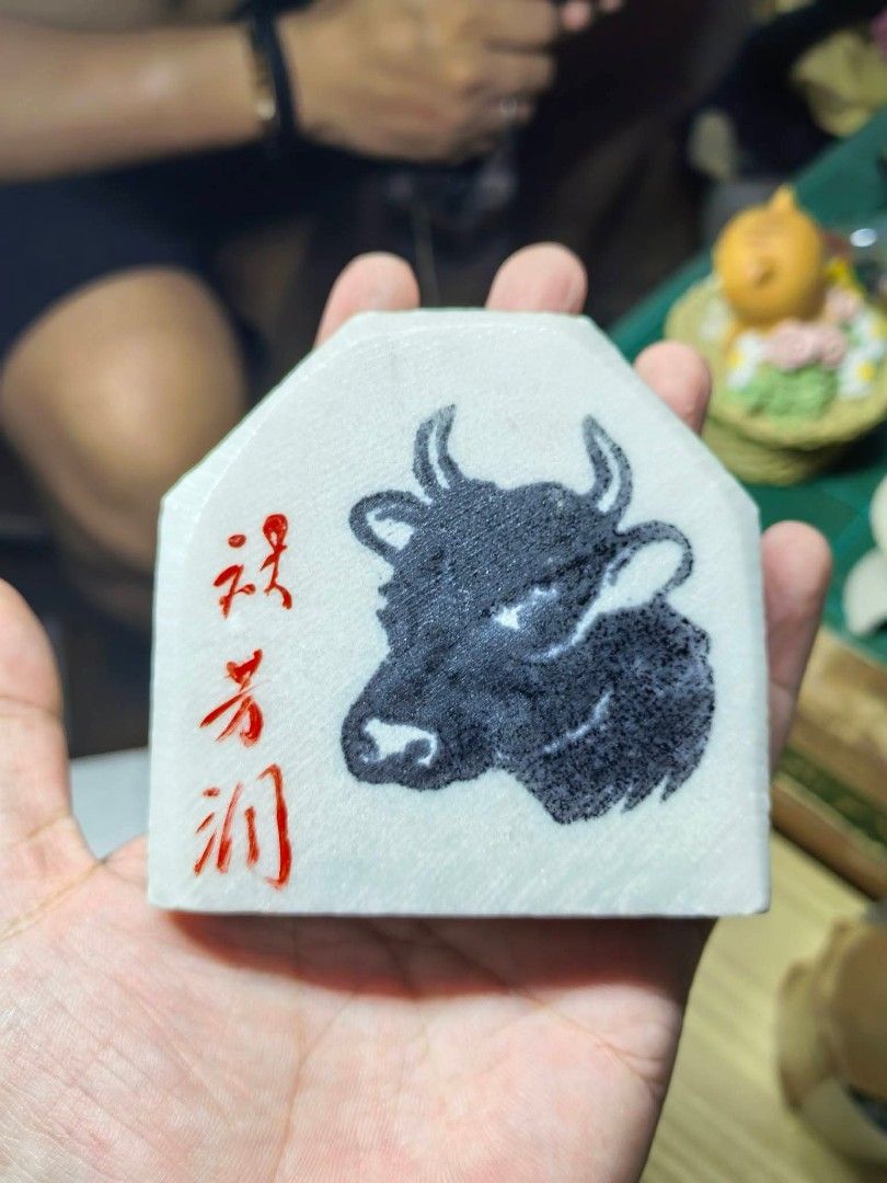 Stone Ox Carving Plaque (Category: Other Home Decor) located in Cebu City. Submitted by dudes_villanueva (Listing ID 1469431568, Image 1). Description: Japanese Marble / Stone Ox Carving Plaque ​Hand-carved and polished white stone/marble plaque featuring a detailed black bull/ox graphic and red Japanese calligraphy characters on the front. The back features blue handwritten markings (60.6.24 土産), indicating it was acquired as a souvenir or gift 