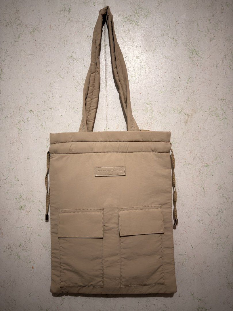Straightforward Sufla Tote (Category: Tote Bags) located in San Pablo. Submitted by yortle (Listing ID 1469423941, Image 1). Description: - Brand: Straightforward - Color: Khaki - Material: Puffer nylon (lightweight & spacious) - Features: Two front slip pockets and secure drawstring top closure - Straps: Two long shoulder straps for comfortable carry - Style: Minimalist daily carryall, perfect for everyday use.