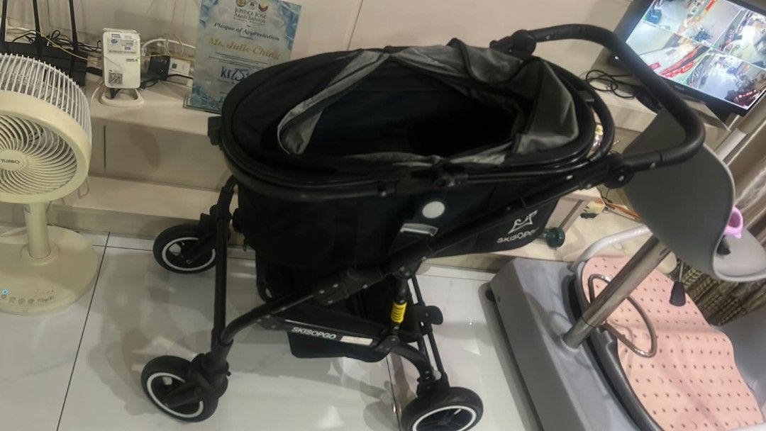 Stroller for pet (Category: Baby Monitors) located in Manila. Submitted by brightstar.b55721 (Listing ID 1469414163, Image 1). Description: Product Description * Item Type: Pet Stroller (Brand: SKISOPGO). * Color: Black frame and main fabric body, with dark grey inner lining along the carrier canopy. * Carrier Compartment: * Features a spacious enclosed fabric carrier compartment with an open canopy top for easy access and ventilation. * Sturdy b