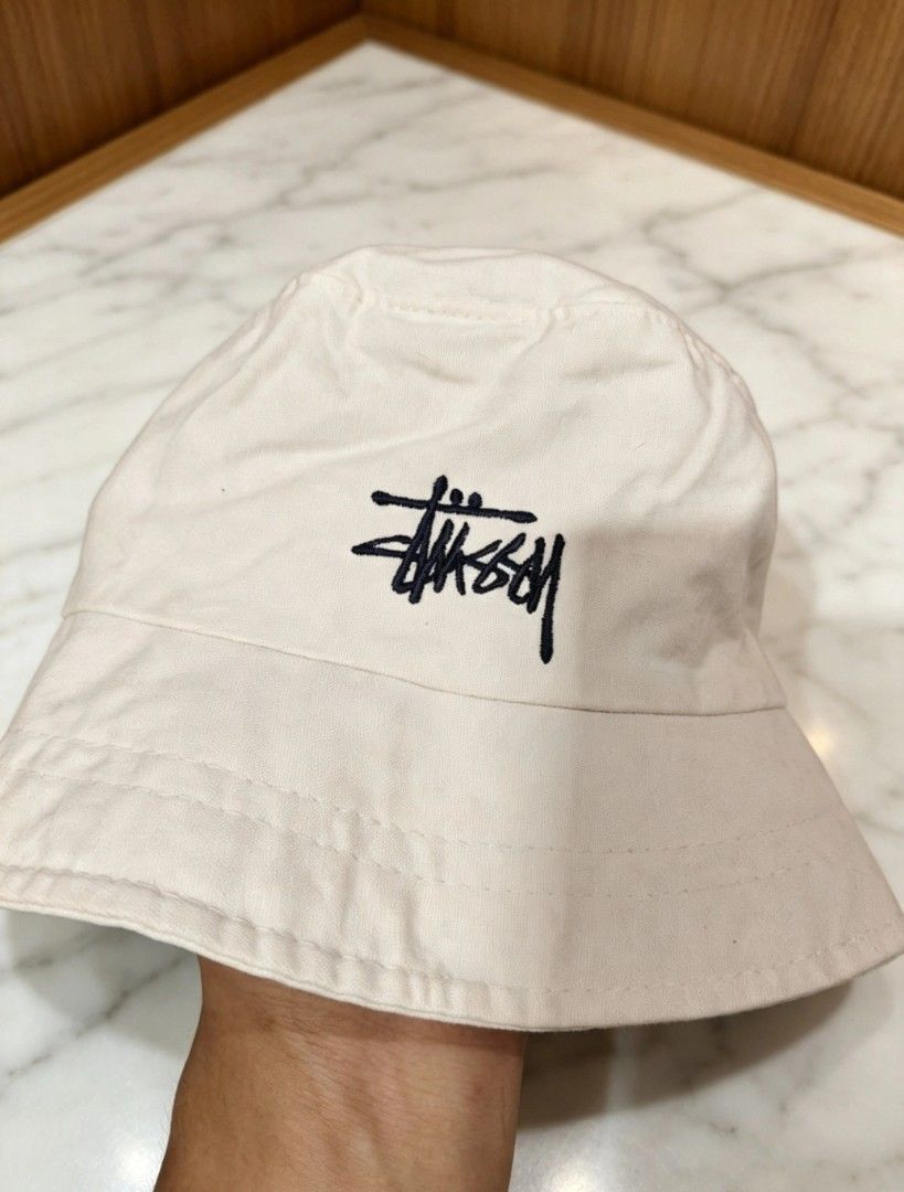Stussy Off-White Bucket Hat (Category: Caps & Hats) located in Manila. Submitted by tabuzomaria1422 (Listing ID 1469453281, Image 3). Description: - Authentic Stussy bucket hat - Color: Off-white - Material: 100% breathable cotton - Design: Classic dark embroidery on front panel - Features: Wide brim for solid sun coverage - Style: Casual streetwear, easy to pair with any outfit - Condition: Brand new / Excellent quality.