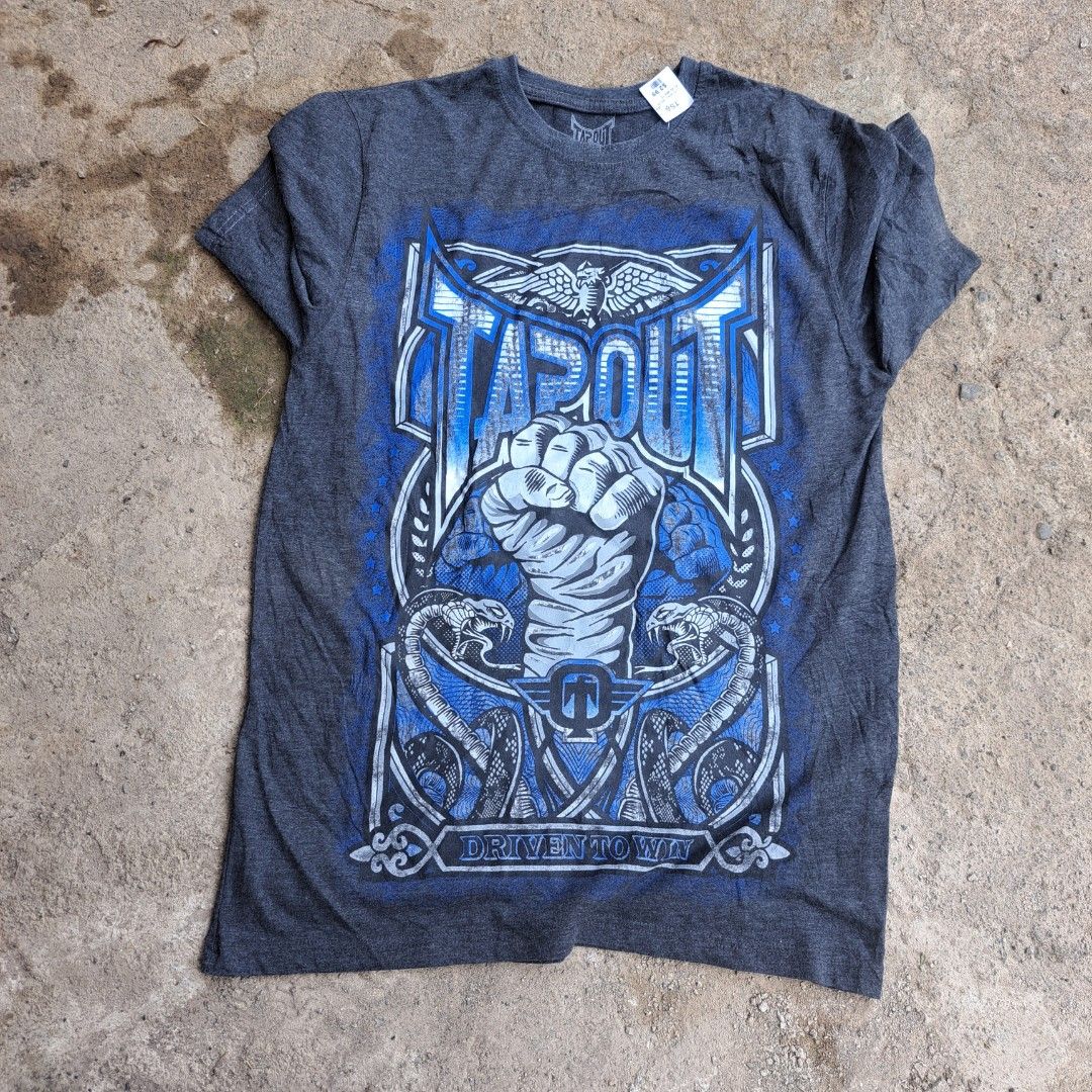 Tapout Graphic Tee Dark Grey Blue Size XL (Category: Tshirts & Polo Shirts ) located in Manila. Submitted by warmphoenix_5fc5b2 (Listing ID 1469540578, Image 1). Description: - Brand: Tapout - Color: Dark Grey - Size: XL - Design: Large blue graphic print with fist, snakes, and 'Driven to Win' text - Material: Soft cotton blend - Style: Short sleeves, crew neck - Shipping or meetups available across the Philippines.