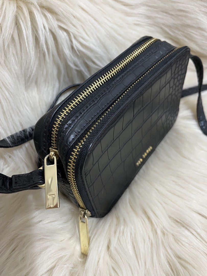 Ted Baker Black Croc Embossed Crossbody Bag (Category: Cross-body Bags) located in Naga. Submitted by ownlineshopp (Listing ID 1469502475, Image 3). Description: - Brand: Ted Baker - Color: Black with chic croc-embossed texture - Hardware: Premium gold-tone details and front logo lettering - Compartments: Secure double zippered compartments - Strap: Long, adjustable crossbody strap - Shape: Structured rectangular silhouette - Condition: Clean ins