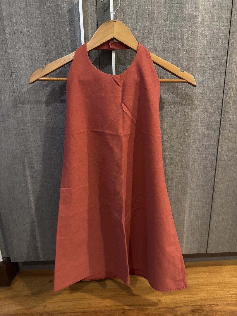 Terracotta Halter Neck Dress Open Back (Category: Dresses) located in Makati City. Submitted by kkk.shops (Listing ID 1469512151, Image 1). Description: - Color: Terracotta orange - Style: Minimalist halter neck dress - Design: Open back with nape button closure - Silhouette: Structured, widens towards the hem - Length: Above the knee - Condition: Excellent, clean fabric with no stains or damage.