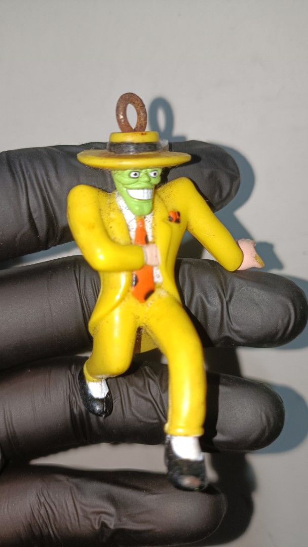 The Mask yellow suit figure keychain (Category: Designer & Blind Box Toys) located in Manila. Submitted by mgabinibentanitonton (Listing ID 1469401867, Image 1). Description: - Vintage 1997 The Mask collectible figurine - Iconic design: green face with wide grin, signature yellow suit and hat - Includes a metal hanging ring on top of the hat for easy display - Stamped with '1997 New Line' and 'Made in China' at the back - Condition: Some rust on 