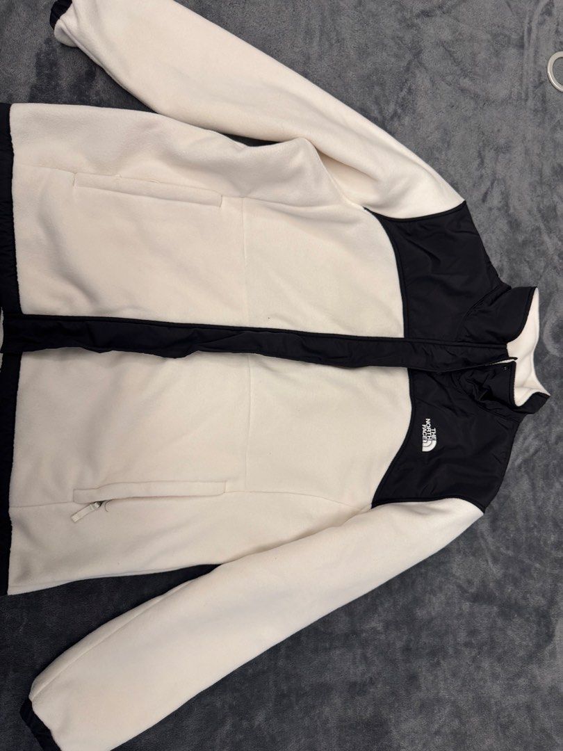 The North Face Circular Design Fleece Jacket (Category: Coats, Jackets and Outerwear) located in Taguig. Submitted by sqaumejada (Listing ID 1469474374, Image 1). Description: - Brand: The North Face - Style: Full-zip fleece jacket with high collar - Color: Cream with contrasting black panels and white embroidered logo - Size: Women's XL (UNISEX) - Features: Secure zip pockets on both sides, soft fleece material - Details: Circular Design tag, ma