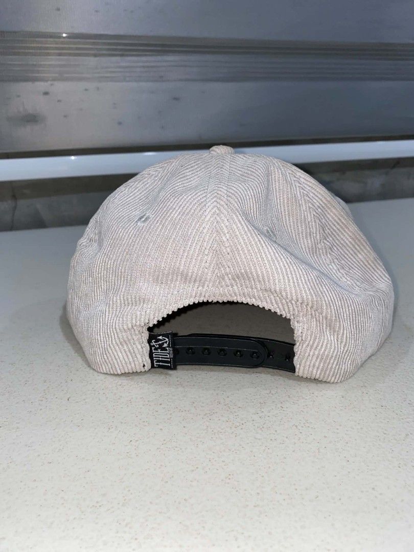 Tide Apparel Corduroy Snapback Cap Beige (Category: Caps & Hats) located in Baler. Submitted by mariokush193815 (Listing ID 1469452102, Image 2). Description: - Brand: Tide Apparel - Material: 100% durable acrylic corduroy - Color: Classic beige with black and white embroidered logo patch - Design: Structured crown with a flat brim - Fit: Adjustable black plastic snapback closure for a custom fit - Details: Includes signature small brand tag on t