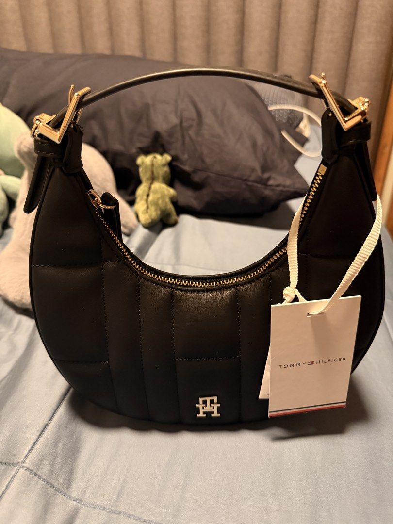 Tommy Hilfiger Black Quilted Shoulder Bag (Category: Shoulder Bags) located in Pasig City. Submitted by joannegin96369 (Listing ID 1469533649, Image 1). Description: Black quilted shoulder bag from Tommy Hilfiger. Gold hardware zip closure across the top. Short strap attached with gold buckles on the sides. Small silver metallic TH logo centered on the front. Original store tag still attached with white string..