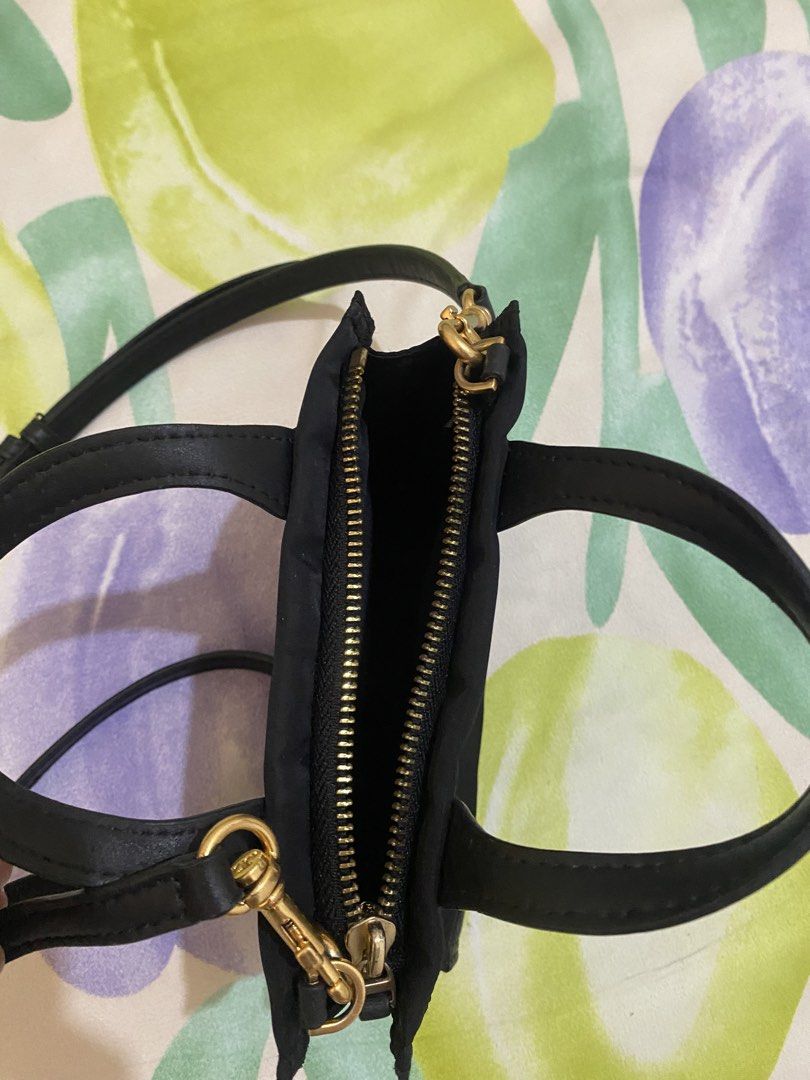 Tory Burch Black Mini Tote Crossbody Bag (Category: Luxury Bags & Wallets) located in Paranaque City. Submitted by chelleann12 (Listing ID 1469445534, Image 3). Description: - Brand: Tory Burch - Material: Durable black nylon with chic leather trim - Logo: Iconic big embossed T logo on the front - Hardware: Premium gold-tone hardware - Straps: Dual top handles plus a detachable, adjustable crossbody strap - Closure: Secure top zip closure - Size: