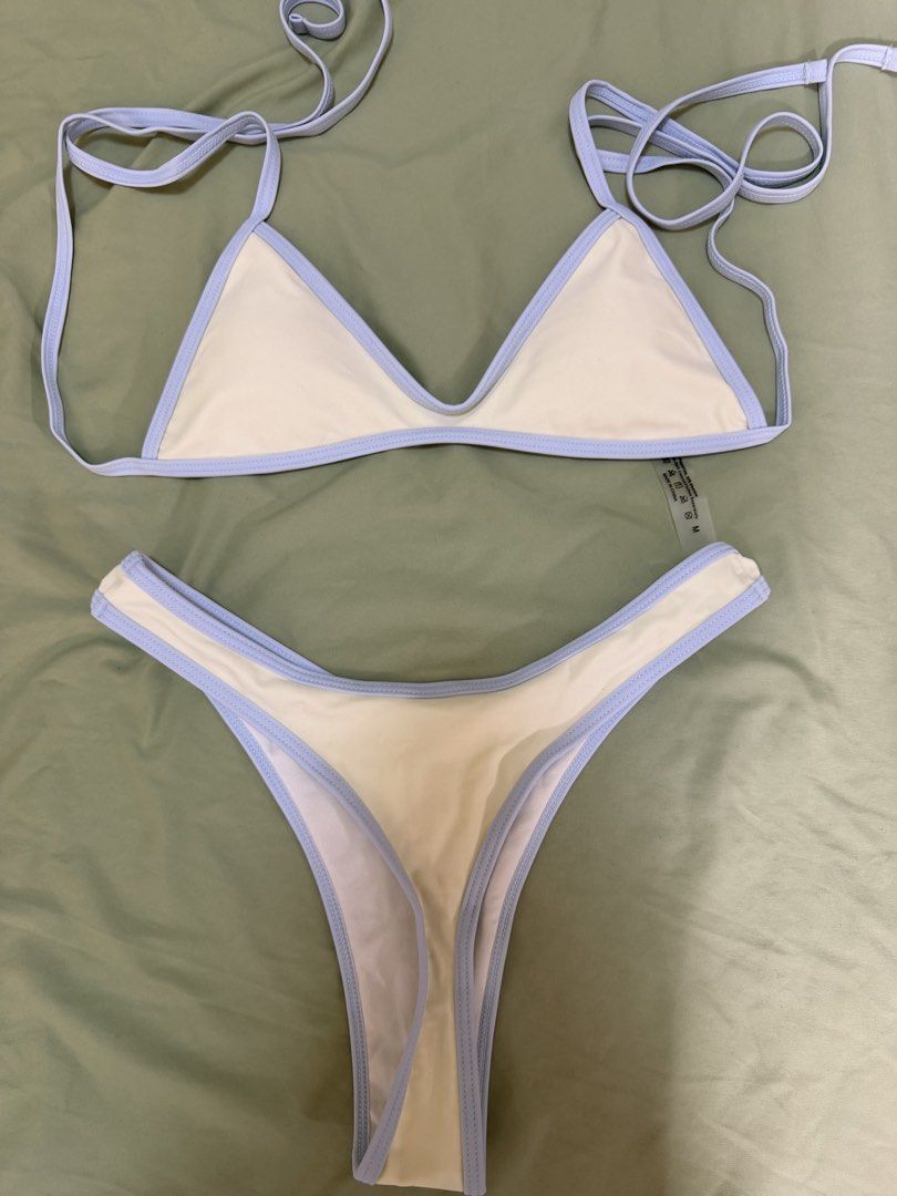 Two-piece bikini set light blue and cream (Category: Bikinis & Swimsuits) located in Makati City. Submitted by andzr. (Listing ID 1469543311, Image 2). Description: - Style: Triangle bikini top with matching high-cut, cheeky bottoms - Color: Cream with light blue trim and piping details - Size: Medium (tag attached) - Material: Polyimide and elastane blend (Made in China) - Care: Hand wash separately - Condition: Clean and neat overall.
