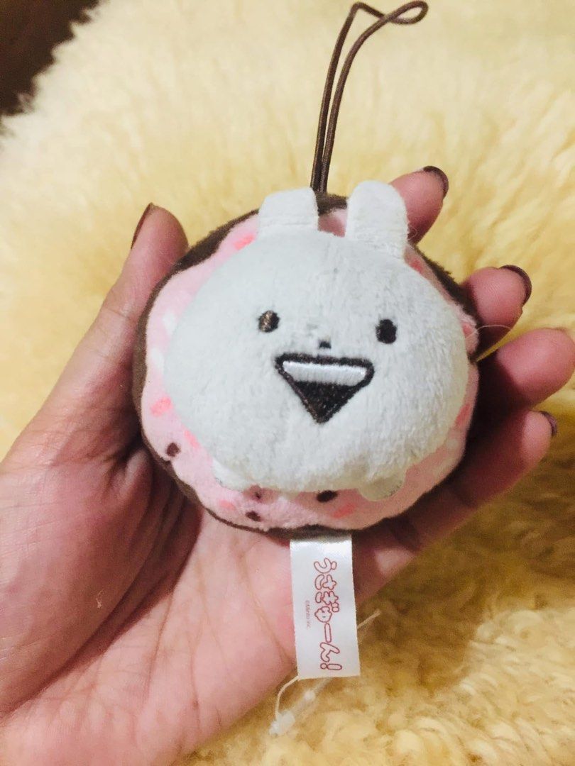 Usamaru Donut Plush Strap Keychain (Category: Plushies & Soft Toys) located in Baguio. Submitted by izza_thrifty (Listing ID 1469567458, Image 2). Description: - Authentic Usamaru character plush keychain - Shaped like a delicious pink frosted donut with chocolate sprinkles - Features the cute white rabbit peeking out from the center - High-quality embroidered facial details - Comes with a brown hanging loop strap and original tag - Clean fabric 