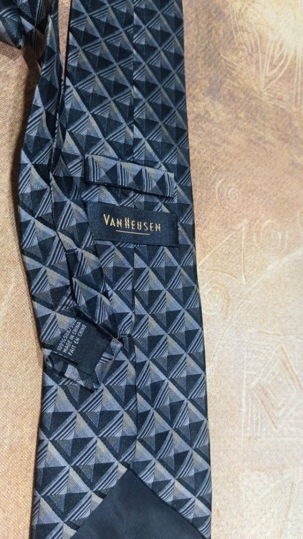 Van Heusen Silk Geometric Pattern Necktie (Category: Ties) located in Cavite. Submitted by navias (Listing ID 1469396350, Image 2). Description: Origin:UAE100% - Brand: Van Heusen - Material: 100% pure silk for a premium feel - Design: Modern geometric triangle pattern in sleek shades of grey and black - Width: Standard blade width suitable for any professional setting - Features: Includes a back keeper loop and original brand label stitched insi