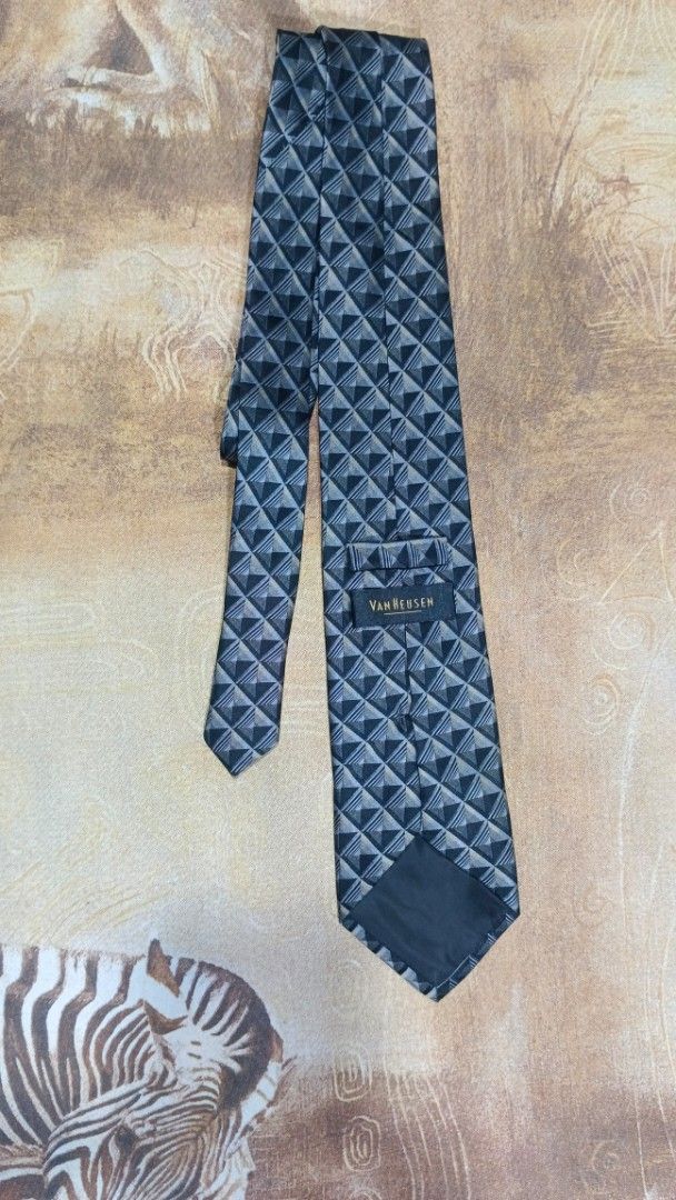 Van Heusen Silk Geometric Pattern Necktie (Category: Ties) located in Cavite. Submitted by navias (Listing ID 1469396350, Image 1). Description: Origin:UAE100% - Brand: Van Heusen - Material: 100% pure silk for a premium feel - Design: Modern geometric triangle pattern in sleek shades of grey and black - Width: Standard blade width suitable for any professional setting - Features: Includes a back keeper loop and original brand label stitched insi