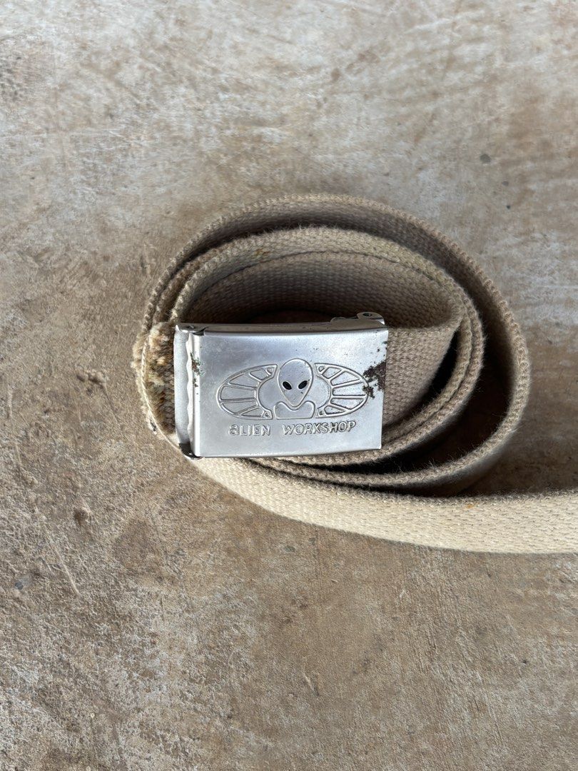 Vintage Alien Workshop Belt (Category: Belts) located in Puerto Princesa. Submitted by 18arc (Listing ID 1469512701, Image 2). Description: • Brand: Alien Workshop (off/legit)(skateboarding/streetwear brand) • Style: Military-style web belt with a flip-tab plaque buckle • Material: Khaki/beige cotton or canvas webbing with a metal tip and buckle • Era: 1990s (Y2K / vintage skate collectible).