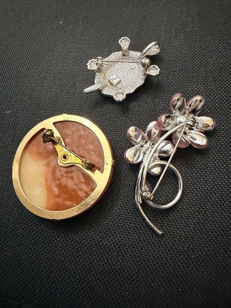 Vintage brooches (Category: Brooches) located in Pasig City. Submitted by smartshopping.ph (Listing ID 1469499953, Image 2). Description: This charming collection of vintage brooches showcases classic mid-century themes, combining romance, nature, and playful figural designs: 1. Victorian-Style “Courting Couple” Cameo Resin Brooch - 700 php 2. Sparkling Rhinestone Turtle Brooch & Pendant: Designed with a striking, highly iridescent pāua (abalone)