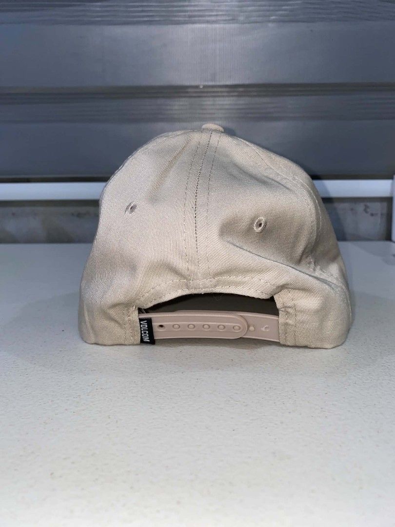 Volcom Stone Company Snapback Cap Beige (Category: Caps & Hats) located in Baler. Submitted by mariokush193815 (Listing ID 1469453415, Image 2). Description: - Brand: Volcom Stone Company - Color: Classic Beige - Condition: Brand new with sticker still attached on the brim - Design: Structured crown with a curved brim - Details: Embroidered Volcom logo patch on the front - Closure: Adjustable plastic snapback with small logo tag - Fit: One Size F