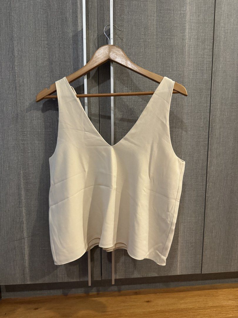 Wear Anika Top (Category: Sleeveless) located in Makati City. Submitted by kkk.shops (Listing ID 1469506924, Image 1). Description: - Color: Cream - Style: Sleeveless tank top with deep V-neckline - Detail: Chic crisscross straps in the back - Fabric: Lightweight and breathable - Versatility: Perfect for pairing with jeans or skirts for a casual look - Condition: Excellent, clean, no stains or marks spotted.