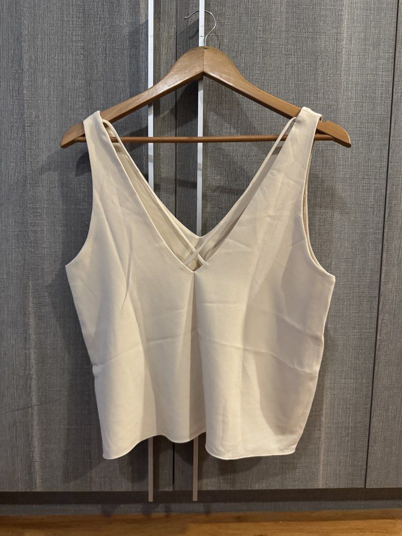 Wear Anika Top (Category: Sleeveless) located in Makati City. Submitted by kkk.shops (Listing ID 1469506924, Image 2). Description: - Color: Cream - Style: Sleeveless tank top with deep V-neckline - Detail: Chic crisscross straps in the back - Fabric: Lightweight and breathable - Versatility: Perfect for pairing with jeans or skirts for a casual look - Condition: Excellent, clean, no stains or marks spotted.