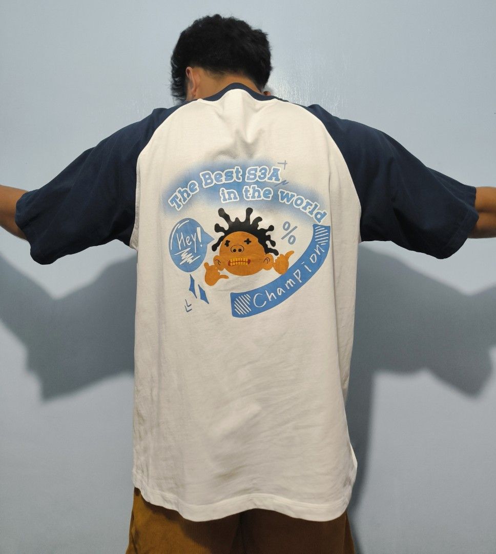 White and Navy Blue Raglan T-Shirt Class Graphic (Category: Shirts) located in Manila. Submitted by astro_mad05 (Listing ID 1469560340, Image 2). Description: - Color: White body with dark navy blue raglan sleeves - Design: Small light blue '09' print on front, large orange cartoon character graphic with 'The Best S3A in the world Champion' text on back - Material: Comfortable cotton - Style: Crew neck, streetwear vibe - Condition: Like New (read
