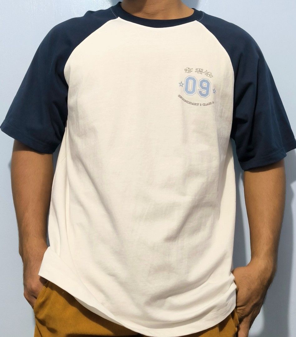 White and Navy Blue Raglan T-Shirt Class Graphic (Category: Shirts) located in Manila. Submitted by astro_mad05 (Listing ID 1469560340, Image 1). Description: - Color: White body with dark navy blue raglan sleeves - Design: Small light blue '09' print on front, large orange cartoon character graphic with 'The Best S3A in the world Champion' text on back - Material: Comfortable cotton - Style: Crew neck, streetwear vibe - Condition: Like New (read