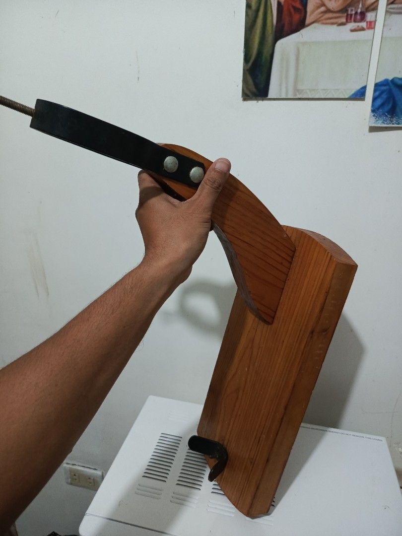 Wooden Ham Holder Stand Jamon Holder (Category: Shelves, Cabinets & Racks) located in Irosin. Submitted by whanchore55263 (Listing ID 1469414562, Image 2). Description: - Solid wooden base with a natural wood grain finish - Curved support arm and durable metal hardware - Top black metal ring with a threaded rod for stability - Base equipped with a metal bracket and spike to securely hold the ham - Sturdy construction, ideal for holiday dinners an