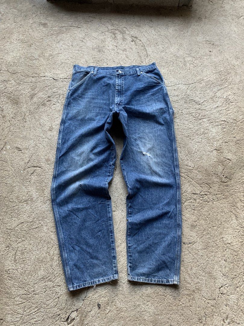 Wrangler Blue Denim Carpenter Jeans (Category: Jeans) located in Olongapo. Submitted by shokii (Listing ID 1469428905, Image 3). Description: - Brand: Wrangler - Style: Classic blue denim carpenter jeans with a relaxed fit - Features: Utility hammer loop, side tool pockets, and logo tag on back pocket - Details: Authentic distressed wear, faded wash, small knee tear, and frayed hems - Material: Heavy-duty 100% cotton denim - Condition: Great vint