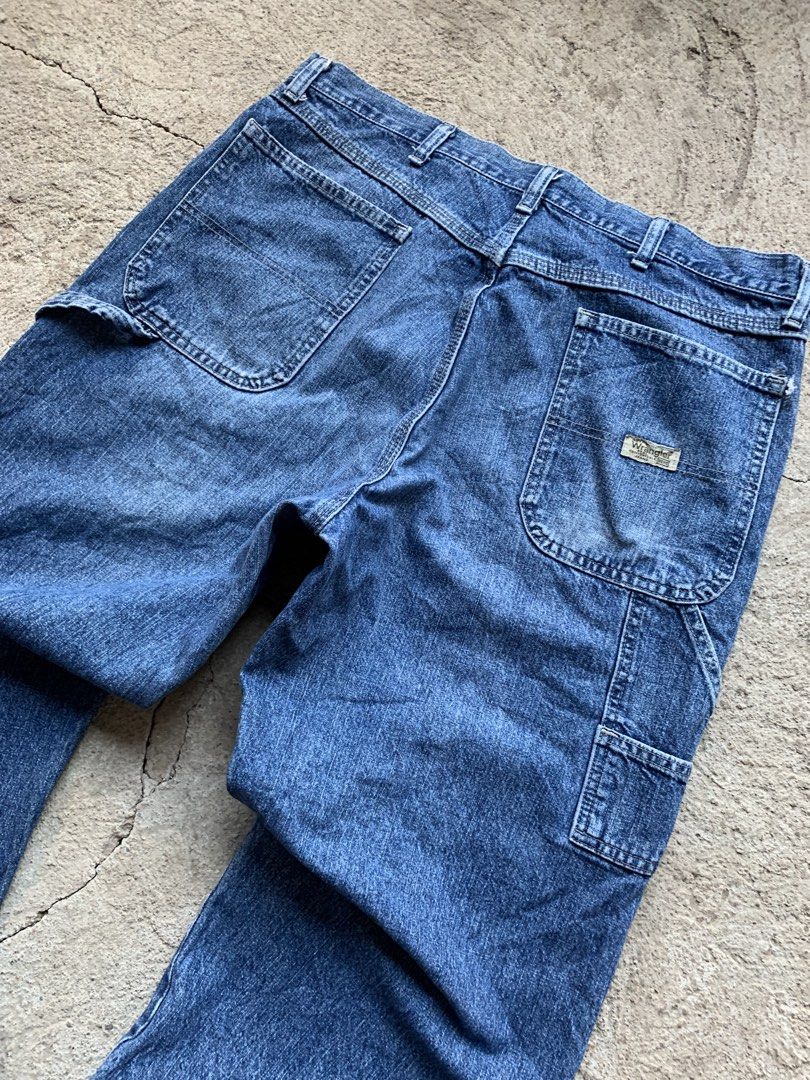 Wrangler Blue Denim Carpenter Jeans (Category: Jeans) located in Olongapo. Submitted by shokii (Listing ID 1469428905, Image 2). Description: - Brand: Wrangler - Style: Classic blue denim carpenter jeans with a relaxed fit - Features: Utility hammer loop, side tool pockets, and logo tag on back pocket - Details: Authentic distressed wear, faded wash, small knee tear, and frayed hems - Material: Heavy-duty 100% cotton denim - Condition: Great vint