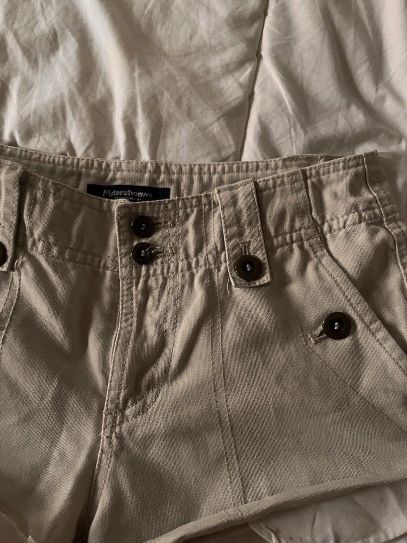 Y2K Low Rise Micro Shorts Vintage (Category: Shorts) located in Manila. Submitted by miyu.ga (Listing ID 1469473200, Image 3). Description: - Brand: Meters/bonwe - Color: Beige - Fit: Relaxed fit with a trendy cut-off curved hem - Closure: Double button waist with belt loops - Pockets: Multiple front pockets with dark brown buttons and cargo details on the back - Details: Sturdy fabric construction with stylish contrast stitching.
