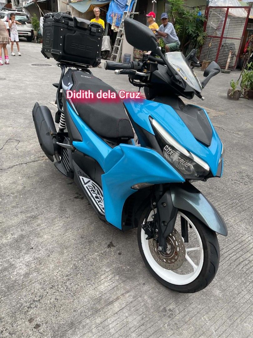 Yamaha Aerox Scooter Bright Blue (Category: Motorbikes for Sale) located in Manila. Submitted by delacruzdi95248 (Listing ID 1469455852, Image 1). Description: Yamaha Aerox scooter in bright cyan blue and black. Fitted with a top storage box on the back rack, windshield, and phone mount on the handlebars. White alloy rims and black seat with red stitching. Odometer reads 25257 kilometers. Runs well, ready for daily commutes or weekend rides aroun