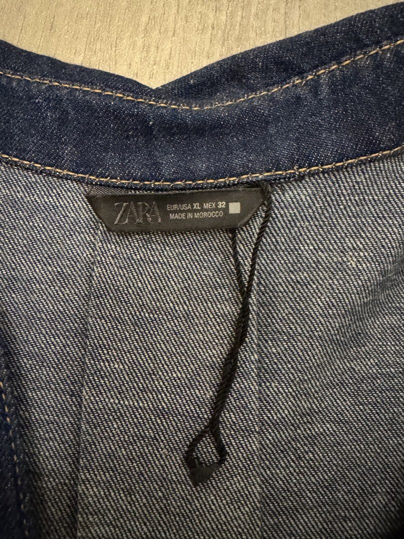 ZARA Denim Button-Down Shirt Size XL (Category: Shirts) located in Taguig. Submitted by sqaumejada (Listing ID 1469415695, Image 2). Description: - Brand: ZARA - Item: Denim shirt - Color: Dark blue wash - Size: EUR/USA XL / MEX 32 - Condition: Brand new with tags attached - Material: Denim with visible grain - Details: Long sleeves, metallic front buttons, classic collar, rounded high-low hem - Origin: Made in Morocco.
