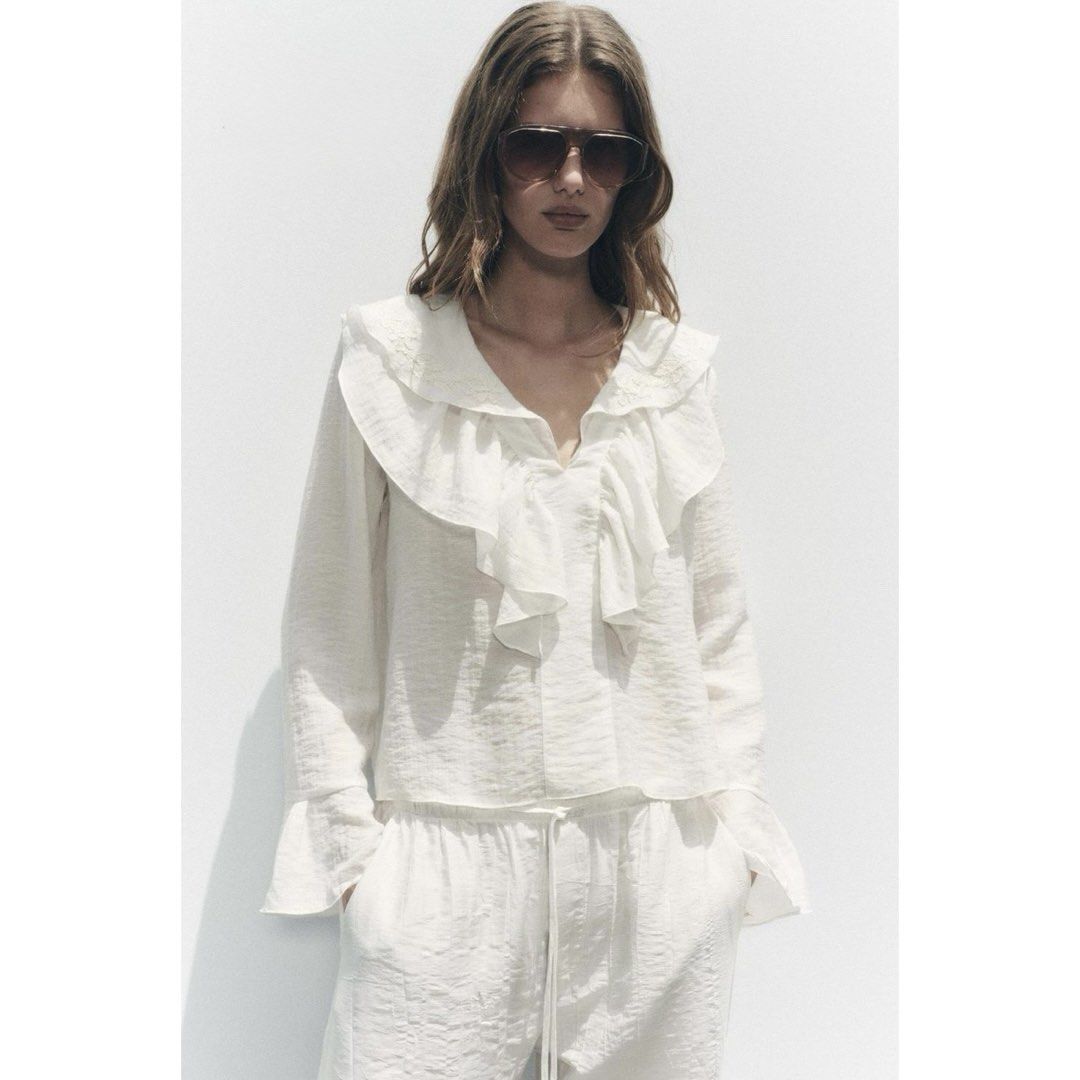 Zara White Embroidered Ruffle Blouse (Category: Blouses) located in Mandaluyong City. Submitted by blzstr (Listing ID 1469433581, Image 1). Description: Ruffled neckline with floral embroidery, V-neck, long sleeves with flared cuffs.