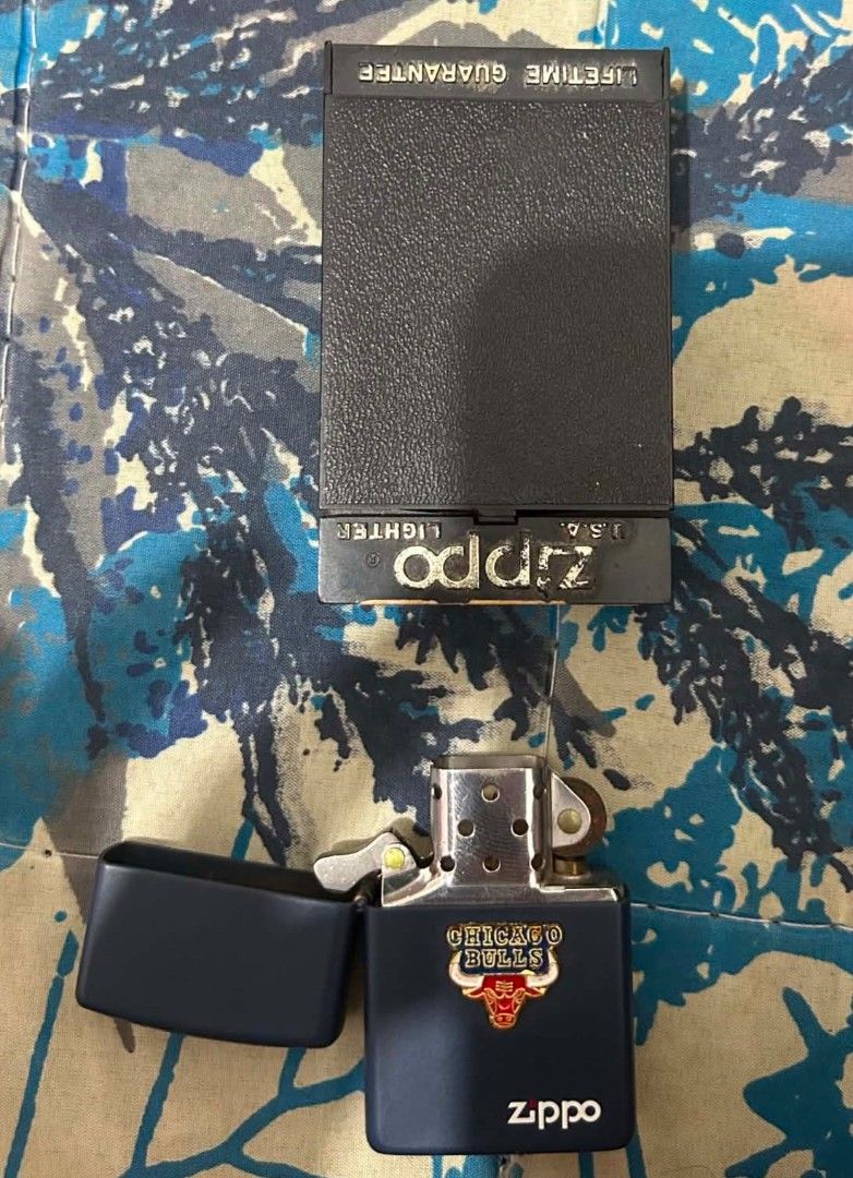 Zippo Chicago Bulls Lighter with Original Box (Category: Vintage Collectibles) located in Manila. Submitted by shomeguro1 (Listing ID 1469449054, Image 1). Description: - Authentic Chicago Bulls Zippo windproof lighter - Stylish matte dark blue finish with team logo emblem - Classic flip-top design with metallic interior insert - Includes original black presentation case with lifetime guarantee - Perfect collectible item for NBA fans and Zippo co